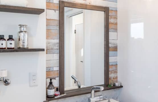 マリンランプの下に、ダークブラウンの木枠の鏡、同色の木製カウンターに置き型の洗面ボウルが設置された造作の洗面化粧台がある、洗面化粧室です。