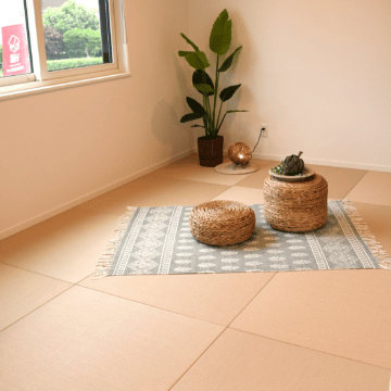 畳の上に藤で編まれたスツールが2つと、和風のランタン、観葉植物が置かれた和室です。