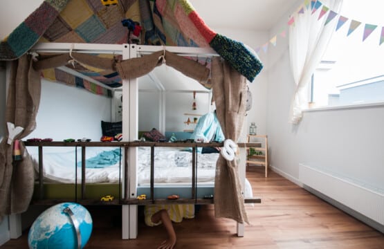 2つのベッドを連結させた子供用ベッドにはパッチワークのラグが掛けられており、麻のカーテンで飾られている。