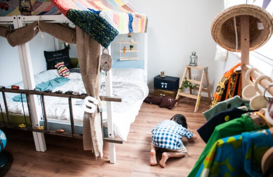 連結されたベッドの下を覗き込む男の子の手前にはウッドラックに子供用の服が並んでいる洋室3です。