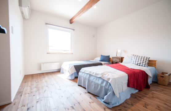 2階の主寝室にはシングルサイズのベッドが2つ置かれていて、ベッドとベッドの間には木製のサイドテーブルが置かれています。