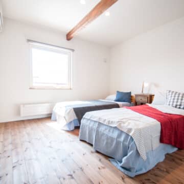 2階の主寝室にはシングルサイズのベッドが2つ置かれていて、ベッドとベッドの間には木製のサイドテーブルが置かれています。