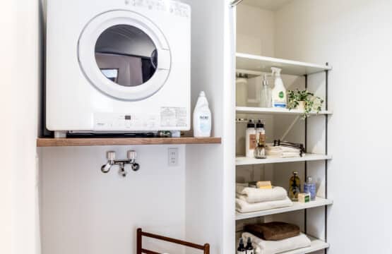 左手側に洗濯機スペース上に棚を取り付け乾燥機を置き、右手側に収納用の白色の可動棚が設置されたランドリー兼脱衣室です。
