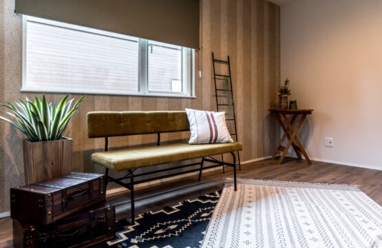 ベージュ系のストライプ柄のアクセントクロスが使われているお部屋で、アイアン脚の緑色のベンチと観葉植物が置かれている2階主寝室です。