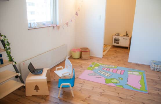 2階の洋室には子供用の木製テーブルと青と白の椅子が設えられています。その奥には子供用のキッチンが置かれています。