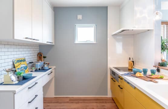 黒色の取っ手の黄色のキッチンと白色のキッチン収納が向かい合わせで配置されたキッチンスペースです。