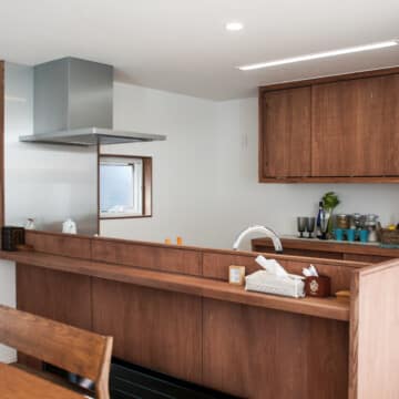 木製のカウンターが備わったキッチンとキッチン収納が向かい合わせで配置されたキッチンスペースです。