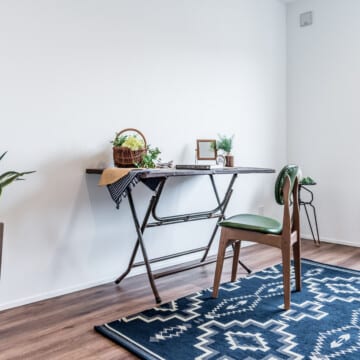 ネイビーのラグの上に、ｋスチール製のヴィンテージのワークテーブルと、木製の緑色の張地のチェアが設えられている2階洋室1です。