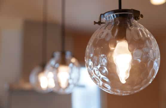 キッチン手元に3灯並ぶ、球体のアンティーク調ガラスシェードのペンダントライトのアップ写真です。