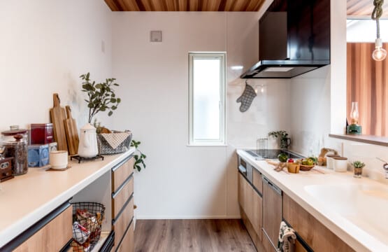レッドシダー調クロスの天井、黒色ライン取っ手の木目調のキッチンと同柄のキッチン収納が向かい合わせで配置されたキッチンスペースです。