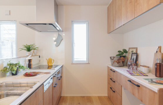ナチュラルオーク色のキッチン本体と収納キャビネットが向かい合わせで設置されている明るいキッチンです。